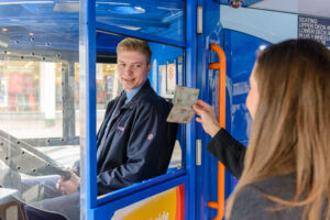 Person getting on the bus showing a ticket to the driver