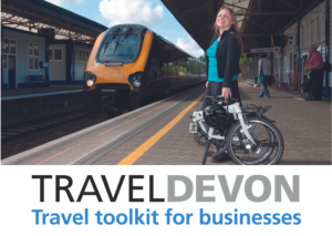 A women standing on a railway platform with a train in the back ground and the Travel Devon Toolkit Logo